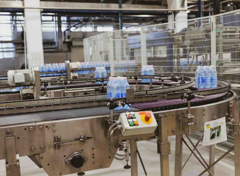Cases of plastic bottles on a moving conveyor belt in a plastic bottle manufacturing plant.